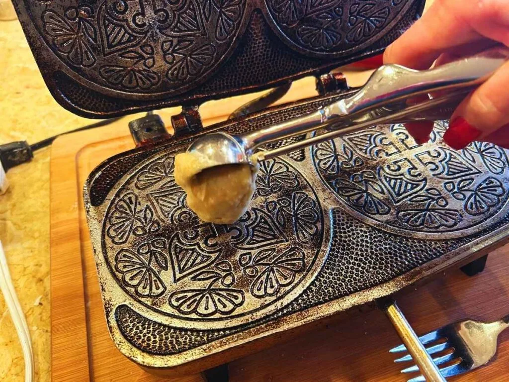 dropping scoop of batter onto krumkake iron