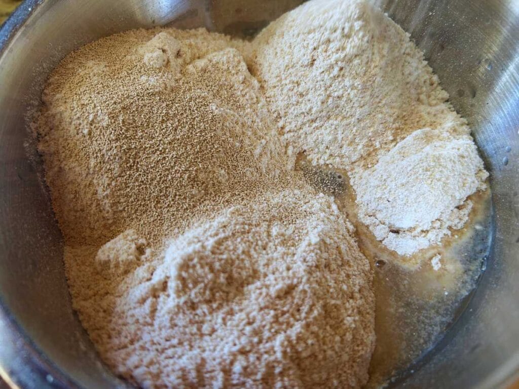 flour and yeast on top of water in a mixing bowl
