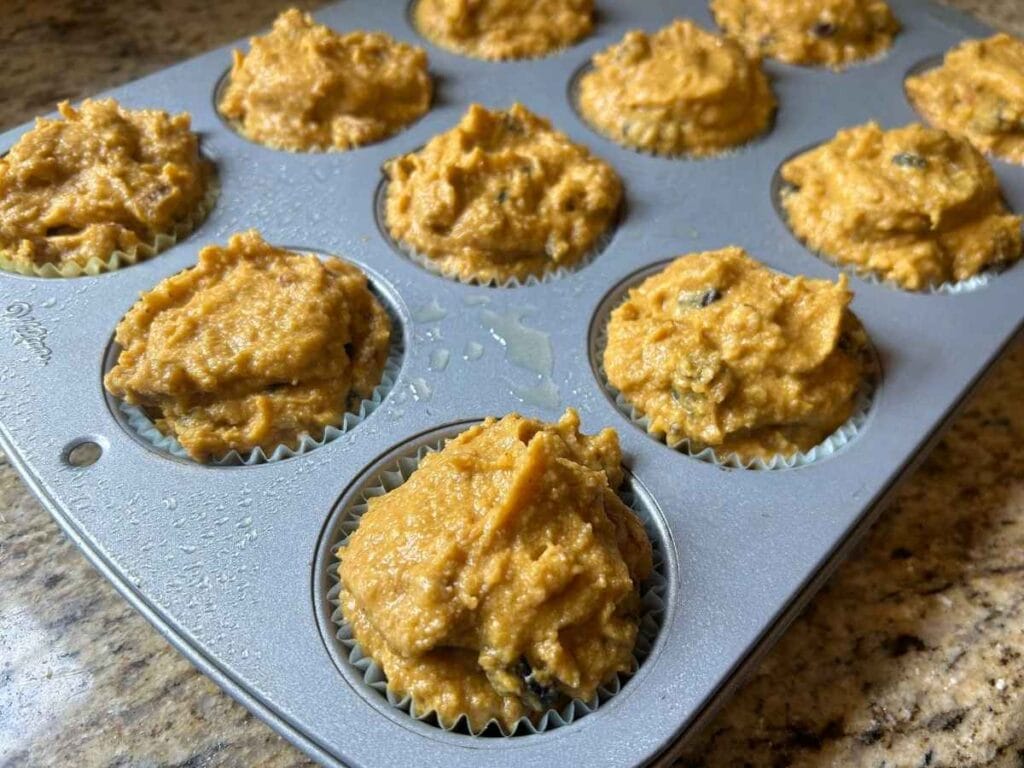 Muffin batter in a muffin tin before baking.