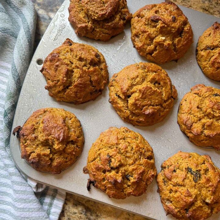 baking pumpkin raisin pecan muffins in a muffin tine next to a green striped towel.