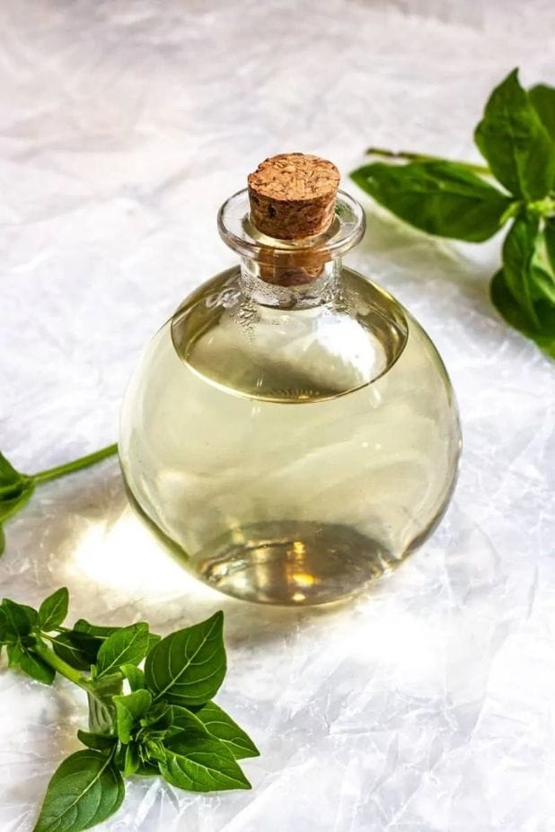 bottle of basil simple syrup surrounded by basil leaves