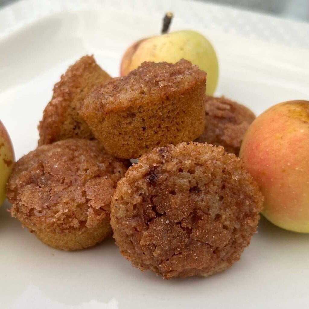 apple cider mini muffins on a white plate with apples