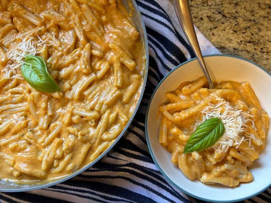 skillet and bowl full of pumpkin mac and cheese