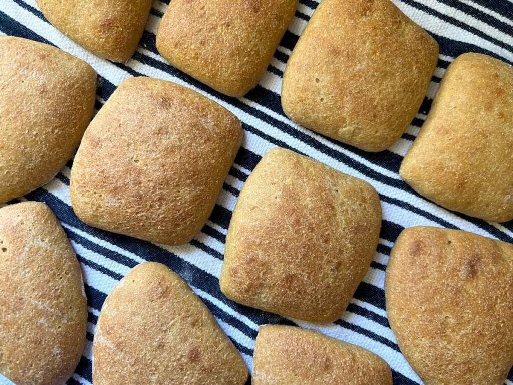baked ciabatta rolls on a navy and white striped towel