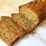 three slices cut off of a loaf of banana bread and laid in front of it