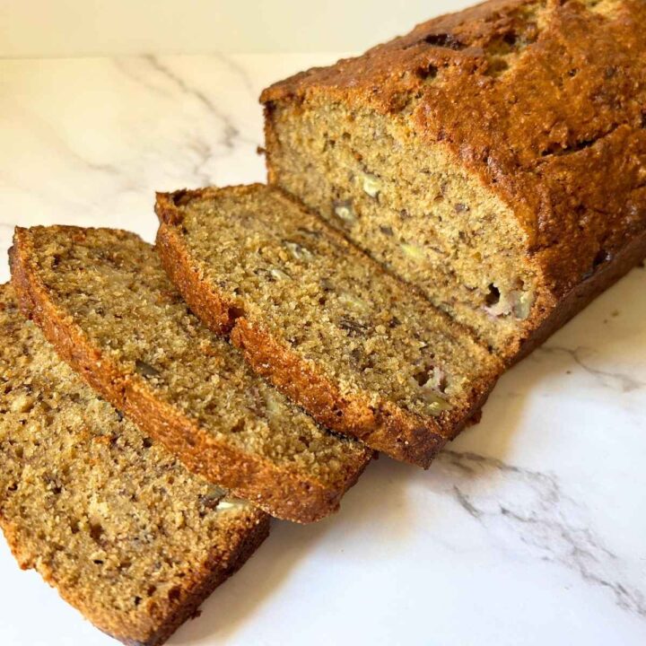 three slices cut off of a loaf of banana bread and laid in front of it