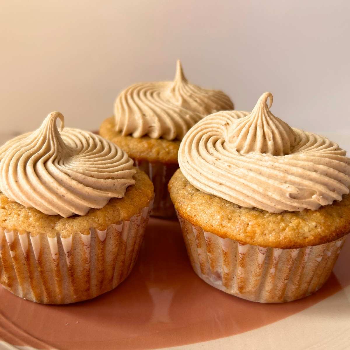 close up of 3 apple pie cupcakes with piped icing on a plate