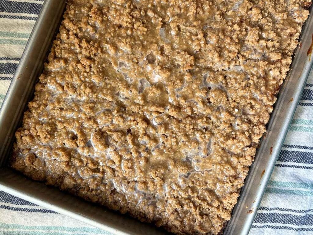 top view of an apple pie coffee cake in the pan sitting on top of a blue striped towel