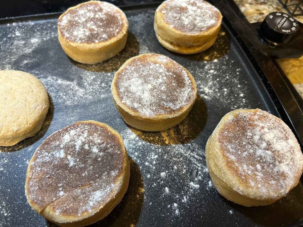 sourdough english muffins cooking on a griddle