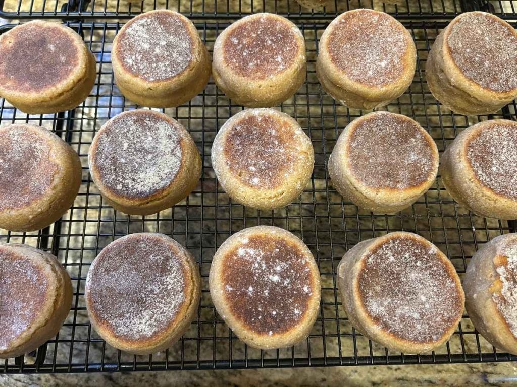 batch of cooked sourdough english muffins on a cooling rack