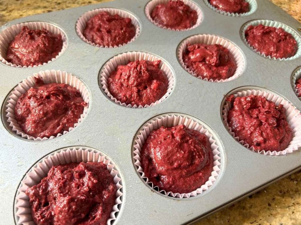 pink muffin batter in the liners in the baking pan
