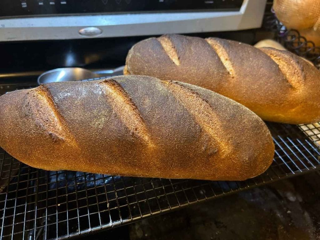 two loaves of country bread on a cooling rack