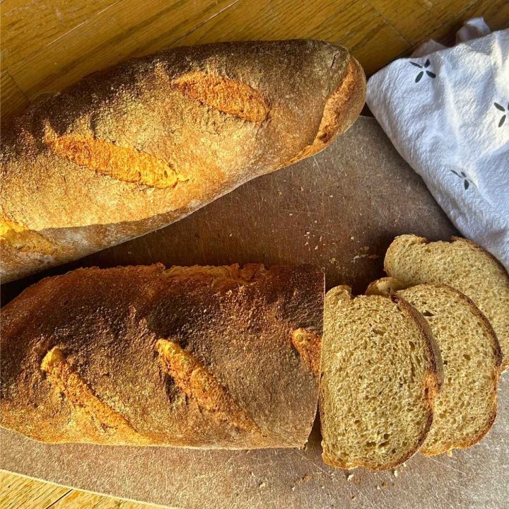 two country loaves on a cutting board with a few slices laid out