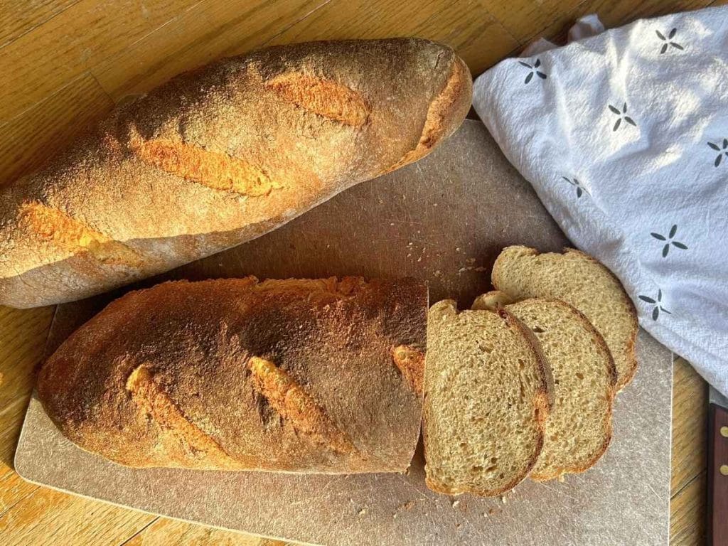 two country loaves on a cutting board with a few slices laid out