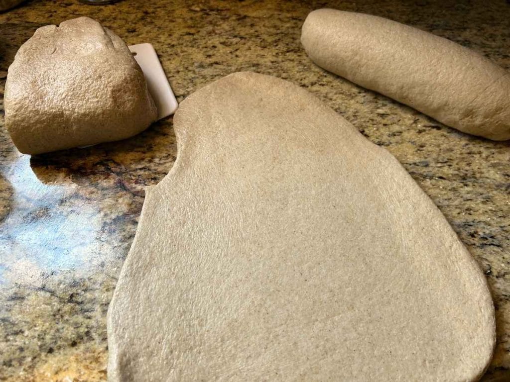 dough rolled out into a triangle shape before being shaped into a loaf
