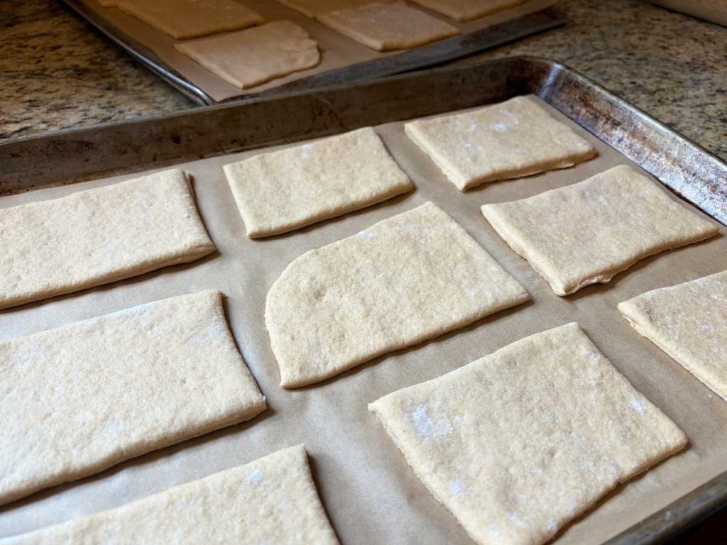 bread dough cut into squares and placed on a parchment-lined baking sheet