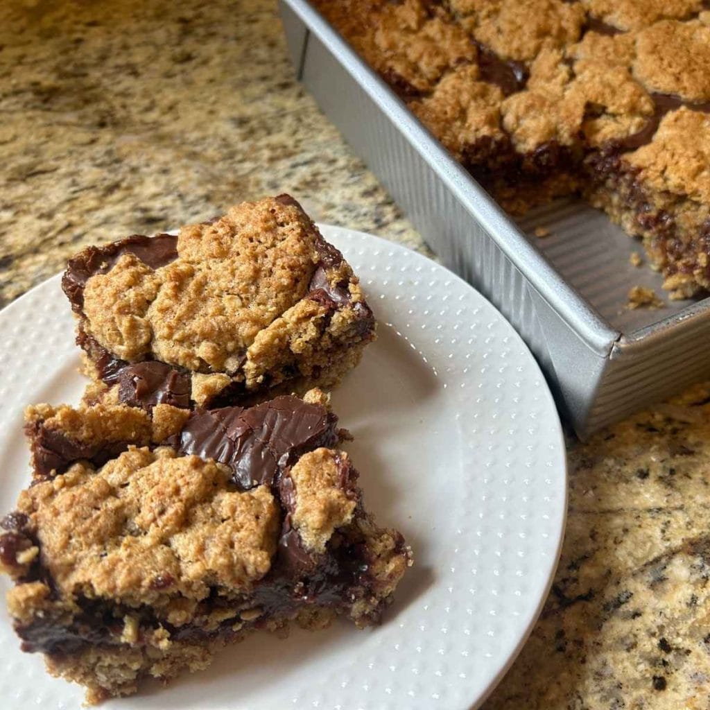 A plate of oatmeal fudge bars made with fresh‑milled flour, cut into neat squares and shown up close.