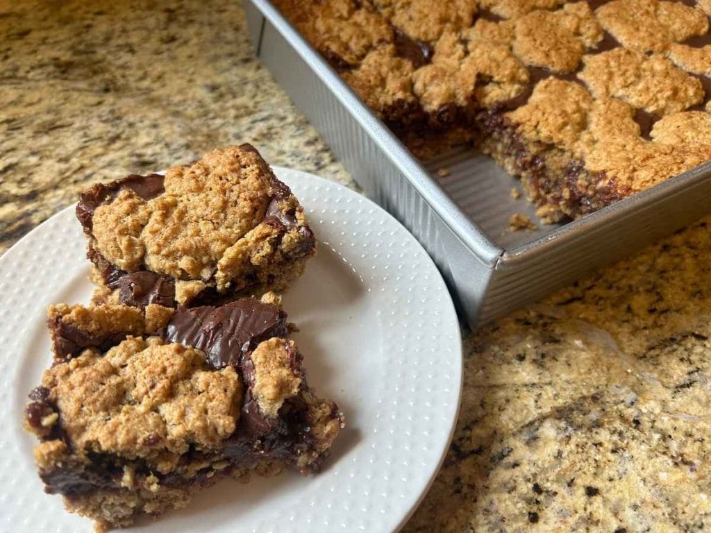 A plate of oatmeal fudge bars made with fresh‑milled flour, cut into neat squares and shown up close.