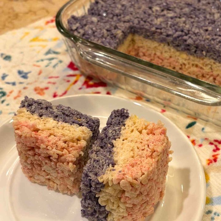 two cut squares of red white and blue rice krispies treats on a plate next to the pan