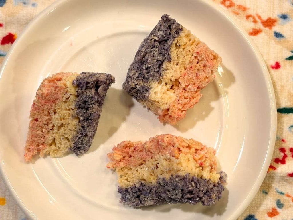 three cut pieces of red white and blue rice krispies treats on a plate next to the pan