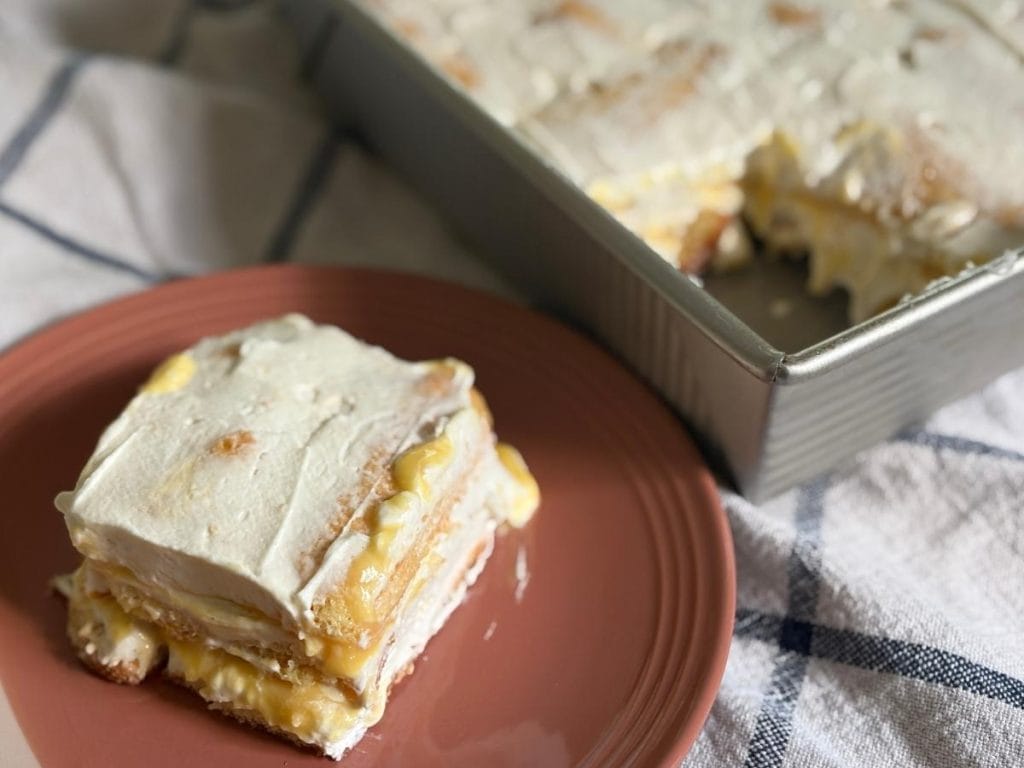 a slice of peach tiramisu on a pink plate in front of the pan