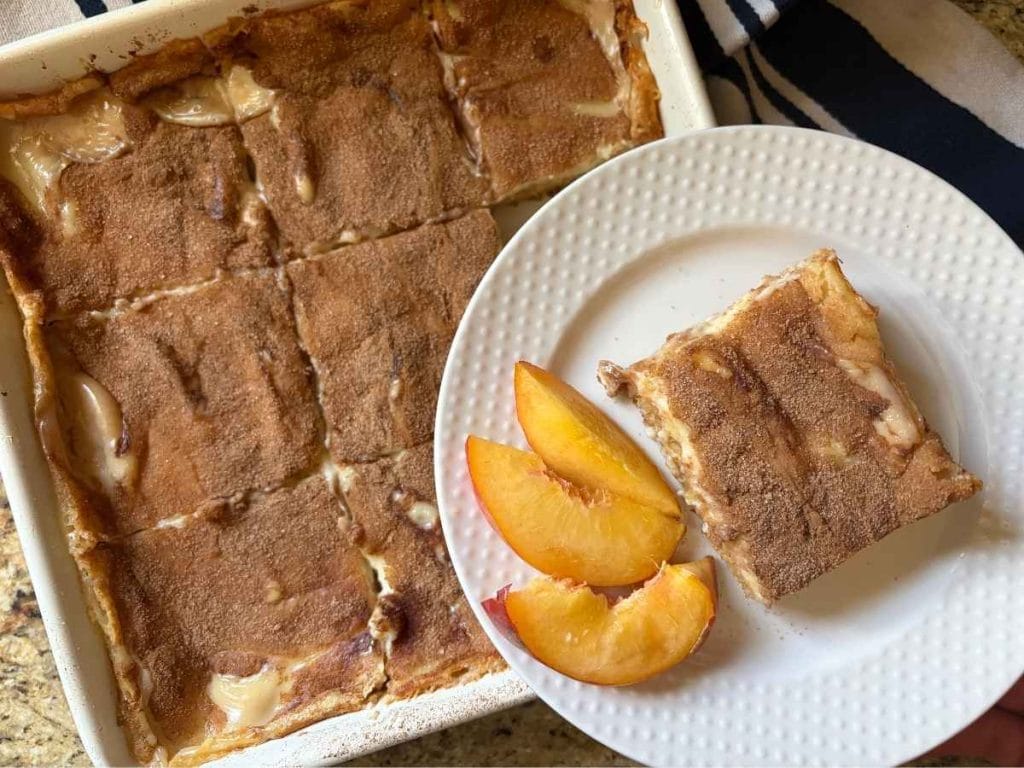 A peaches and cream cake with sliced peaches, shown in a bright, close-up overhead view