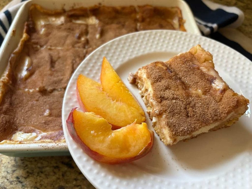 A peaches and cream cake with sliced peaches, shown in a bright, close-up view