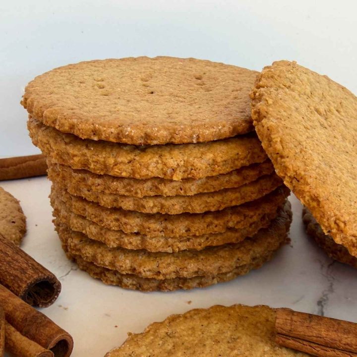stack of thin, crispy cookies next to cinnamon sticks