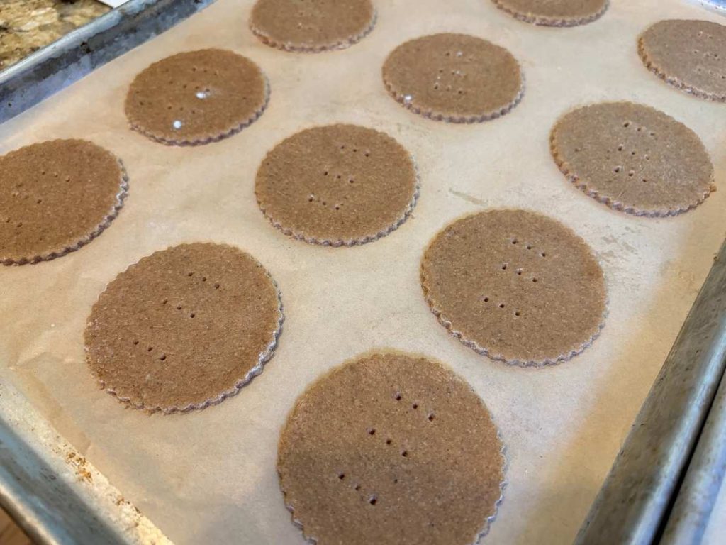 round crackers on a baking sheet with holes poked in the middle